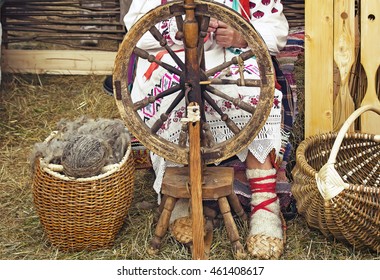 Near an old spinning wheel sits an elderly woman in national costume and worked on it, spinning. - Powered by Shutterstock