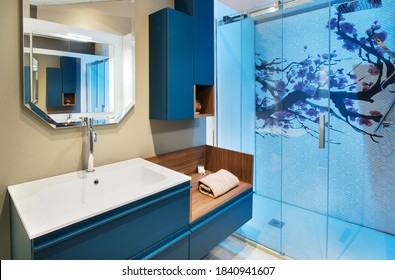 Neat Bathroom Interior With Blue Shower Cubicle And Wall Mounted Cabinet And Vanity With Fresh Rolled Towel Under A Mirror With Reflection