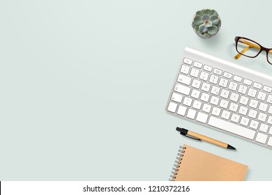 Neat And Clean, Well Organized Home Office Workspace With Technical Gadgets, Writing Supplies, Computer Keyboard, Glasses And A Potted Succulent Plant On A Mint Background