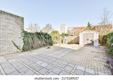 Neat Cobbled Patio With A Wooden Bollard And An Ivy-covered Fence