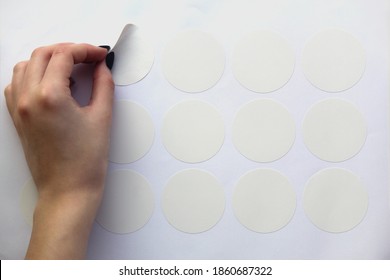 A Neat Female Hand Peels Off The Round White Sticker Of The Plotter Trimming.  Mockup Stickers