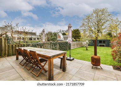 Neat Paved Patio With A Seating Area And A Small Garden Near A Wooden Fence