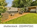 Neat paved patio with sitting area and small garden near wooden fence