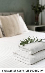 Neat stack of folded towels placed on a bed, ready for use. Morning in cozy apartment with guest bedroom. Comfort living ideas, concepts of cleaning service in hotel rooms