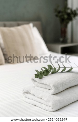 Neat stack of folded towels placed on a bed, ready for use. Morning in cozy apartment with guest bedroom. Comfort living ideas, concepts of cleaning service in hotel rooms