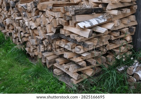 Neat stack of split wooden logs prepared for winter heating outdoors on grass