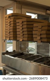 A neat stack of takeout boxes is displayed above a wellorganized food prep area with stainless steel containers