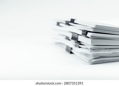 A neat stack of white papers secured with multiple black binder clips, symbolizing organization and paperwork