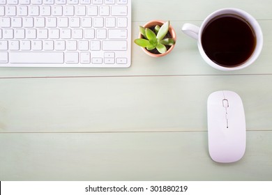 Neat Workstation On A Wooden Desk Viewed From Overhead With A Wireless Computer Mouse And Keyboard, Cup Of Coffee And Houseplant