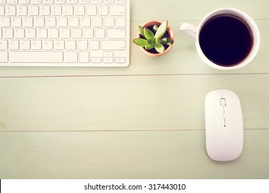 Neat Workstation On A Wooden Desk Viewed From Overhead With A Wireless Computer Mouse And Keyboard, Cup Of Coffee And Houseplant