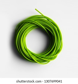 A neatly coiled wire close-up top view isolated on a white background. Green fishing line.