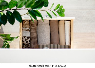 Neatly Folded Clothes Of Brown Flowers In A Drawer, Top View, A Branch Of A Green Houseplant With Large Leaves