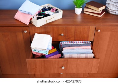 Neatly Folded Clothes In Wooden Drawer