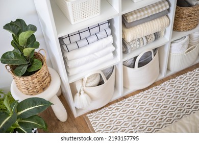Neatly folded linen cupboard shelves storage at eco friendly straw basket placed closet organizer drawer divider. Stacks towels pillows plaids soft sheets bedding cabinet filling Nordic organization