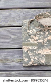 Neatly Folded Military Jacket. Wooden Desk Table Background.