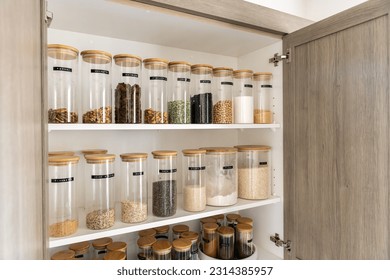 Neatly organized labeled food pantry in a home kitchen with spices grains flour rice sugar nuts