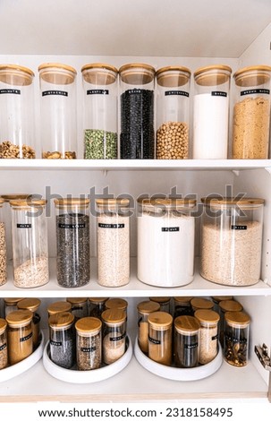 Neatly organized labeled food pantry in a home kitchen with spices in glass wooden spice jars