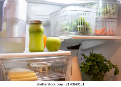 Neatly Organized Open Refrigerator Containing An Assortment Of Fresh Produce And Celery Juice