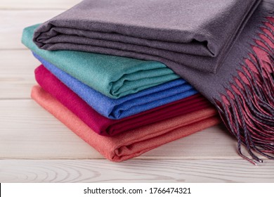 Neatly stacked piles of cashmere stoles, shawls, scarves of different colors. Women's accessory, gift souvenir. Studio shot.
