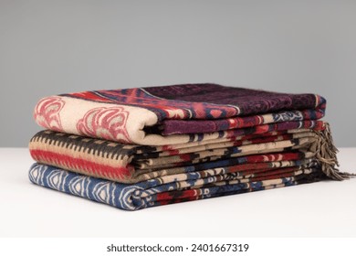Neatly stacked piles of cashmere stoles, shawls, scarves of different colors. Women's accessory, gift souvenir. Studio shot. - Powered by Shutterstock