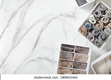 Neatly And Tidy Folded Lingeries In Organizer Drawer Divider On White Marble Background. Decluttering Of Undergarments. Organized Space And Drawer Storage. Copyspace.