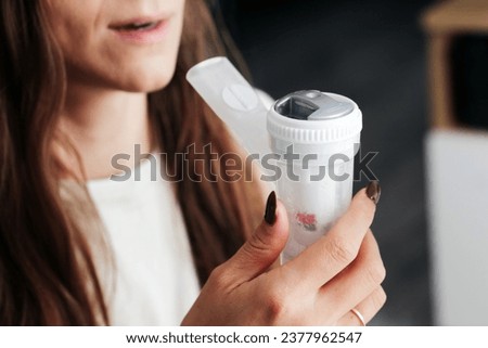 Nebulizer device in mouth. Woman with inhaler in her mouth background. Breathing saline through nebulization. Mouth inserted nebulizer. Lung and throat treatment. Vapour mouth.