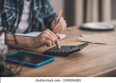 Necessary calculations. Man using a calc and other gadgets for financial estimation