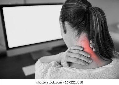 Neck Ache Concept. Young Woman Sitting At Office Desk Feeling Hurt Having Pain In Her Neck.Woman Massaging Rubbing Stiff Sore Neck Tensed Muscles, Fatigued From Computer Work And Incorrect Posture.