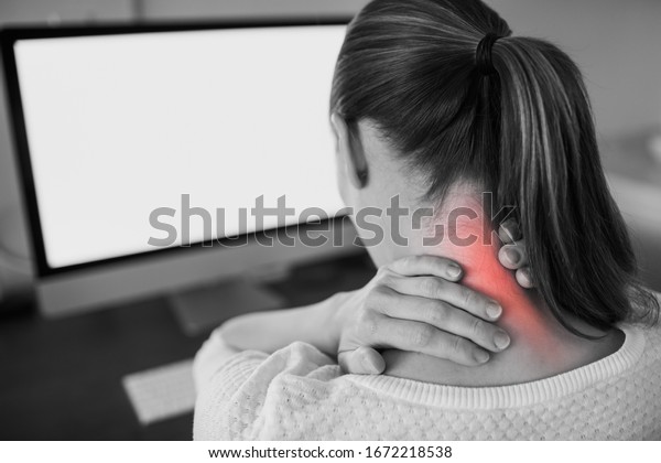 Neck ache concept. Young woman sitting at office\
desk feeling hurt having pain in her neck.Woman massaging rubbing\
stiff sore neck tensed muscles, fatigued from computer work and\
incorrect posture.