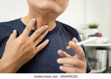 Neck of male smoker have a sore throat,painful and inflammation caused by smoking,man patient holding a cigarette has phlegm in his throat suffering from laryngeal cancer,throat cancer disease concept
