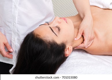 Neck massage in spa. Female beautician work in wellness center. Professional massagist make relax healthy procedure to beautiful indian girl in cosmetology cabinet or beauty parlor.