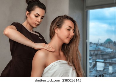 Neck massaging procedure to middle age female in beauty SPA salon. Masseur woman doing medical therapy neck massage for adult slender lady. Healthy lifestyle, well-being concept. Copy ad text space - Powered by Shutterstock