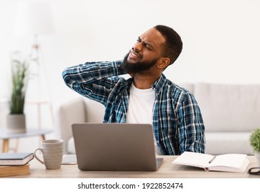 Neck Pain. Black Man Suffering Massaging Aching Neck Having Painful Strain After Computer Work Sitting At Workplace In Modern Office. Arthritis And Poor Posture At Laptop Problem. Selective Focus