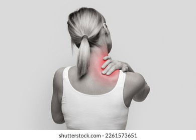 Neck pain muscle stress and strain concept. Stressed blonde woman massaging red sore neck, back view, black and white photo, studio background, copy space - Shutterstock ID 2261573651