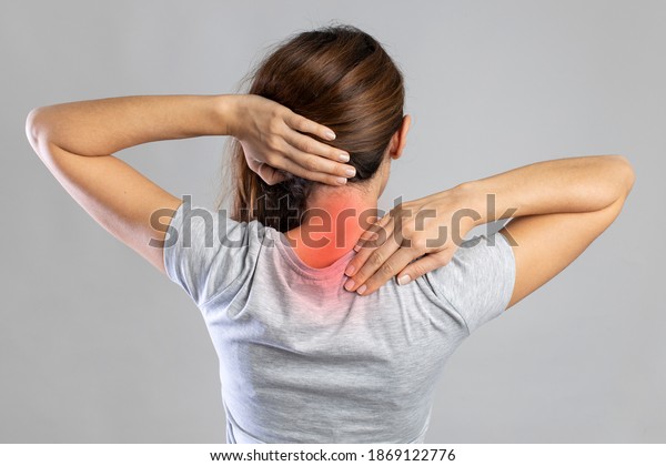 Neck pain, woman with backache on gray background,\
studio shot