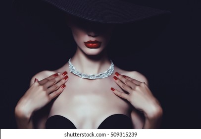 A necklace of diamonds on the neck of a luxurious woman in a hat.
