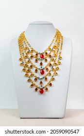 The Necklace Is Made Of Gold And The Gemstone Is On Stand.