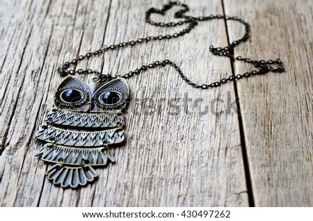 Necklace with an owl on a wooden background. Women's accessories