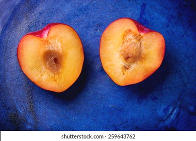 Nectarine halves in the shape of heart over blue ceramic background. Top view.