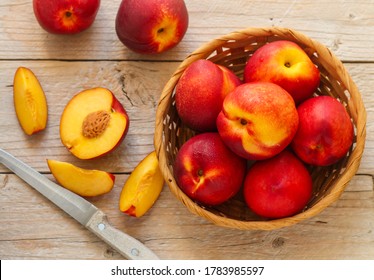 Nectarine. Ripe juicy organic nectarines (peaches) in a wicker basket. Whole and sliced fruit on a wooden table. Selective focus, top view