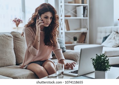 Need A Doctor. Sick Young Women Talking On Smart Phone And Using Computer While Sitting On The Sofa At Home   