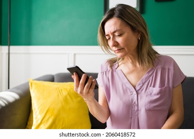 I Need My Glasses. Caucasian Mature Woman With Eye Sight Problems Trying To Read A Text On Her Smartphone