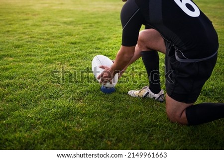 I need to score this. Cropped shot of an unrecognizable sportsman crouching alone during rugby practice in a sports club.
