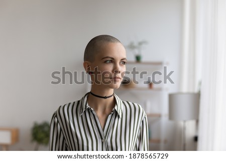 Need for self expression. Thoughtful stylish millennial woman with extra short hair non formal youth subculture representative pondering. Pretty young teenage female with shaved head looking at window