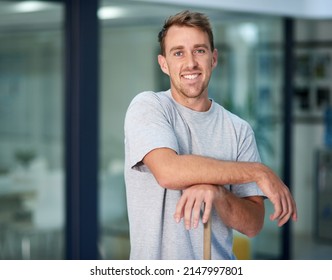 Need Something Cleaned Im Your Man. Portrait Of A Young Man Leaning On A Mop While Cleaning The Office Floor.