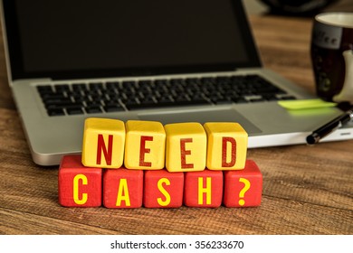 Need Cash? Written On A Wooden Cube In A Office Desk