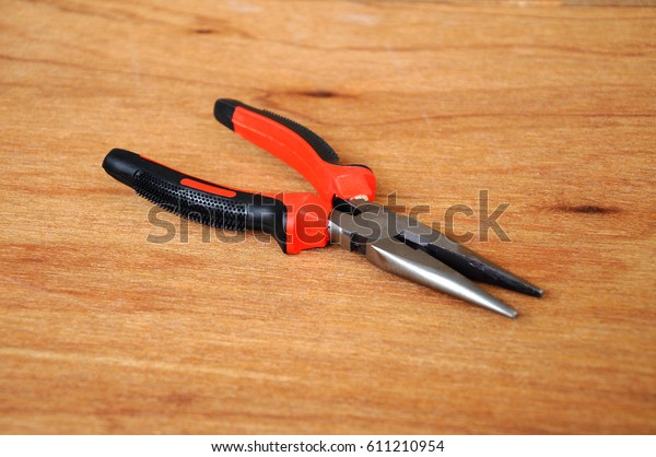Needle Nose\
Pliers also known as pointy nose pliers or long nose pliers\
isolated on wood grain texture background.\
