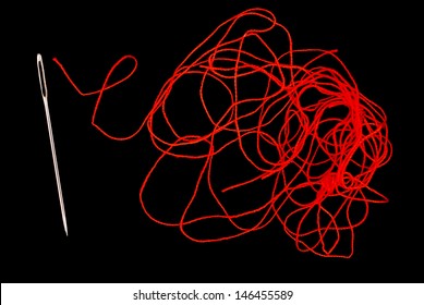 Needle and red thread on black background