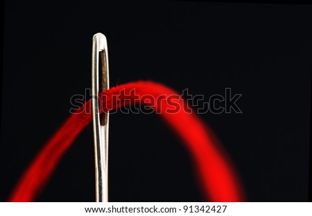 needle with a red thread on a black background