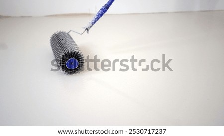 Needle roller is being used to level and remove air bubbles from a freshly poured epoxy floor